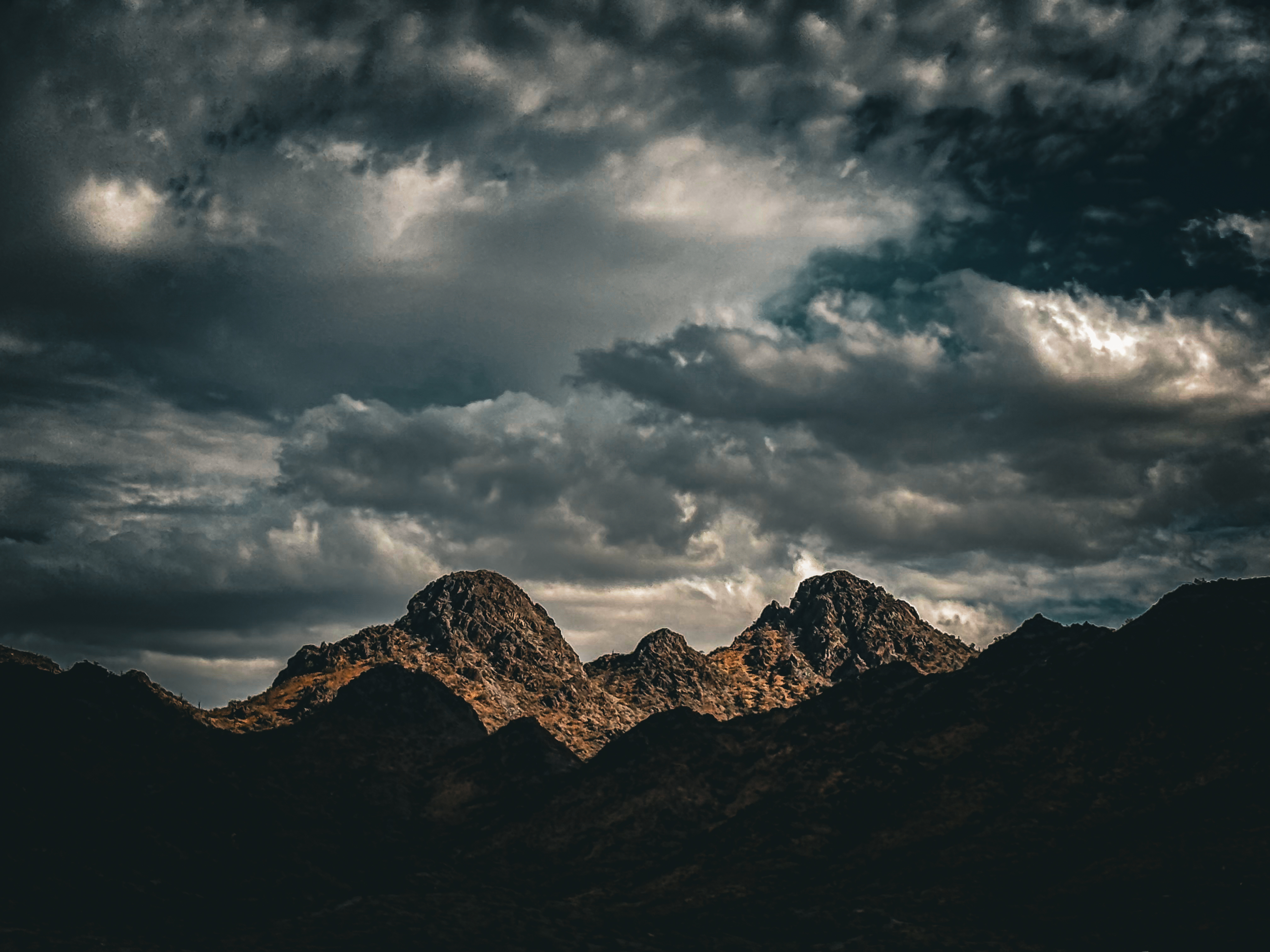 Mountain peaks catching golden light under dramatic storm clouds